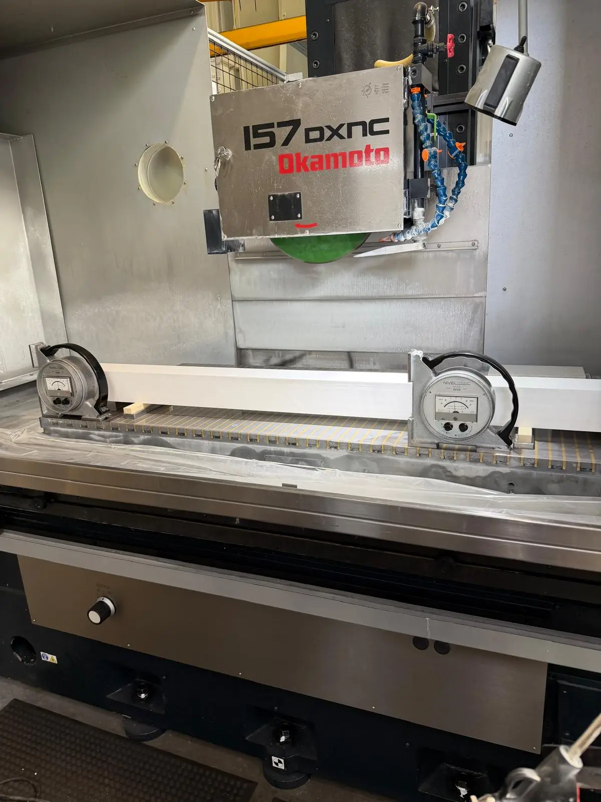 Zwei elektronische Libellen stehen auf einem Präzisionslineal quer über dem Tisch einer Flachschleifmaschine Okamoto 157 DXNC.